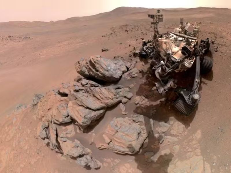 NASA unveiled a new Perseverance rover selfie from its Mars exploration since 2021. The image highlights part of the Martian landscape inside the ancient Jezero Crater, featuring rocky terrain and towering cliffs.